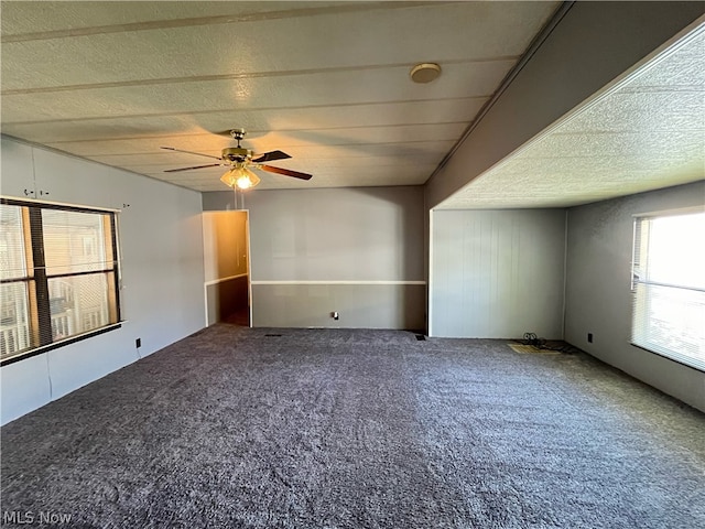 empty room featuring a textured ceiling, carpet floors, and ceiling fan