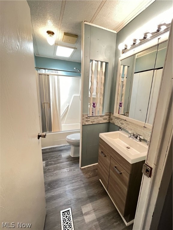 full bathroom featuring tasteful backsplash, toilet, large vanity, wood-type flooring, and bathing tub / shower combination