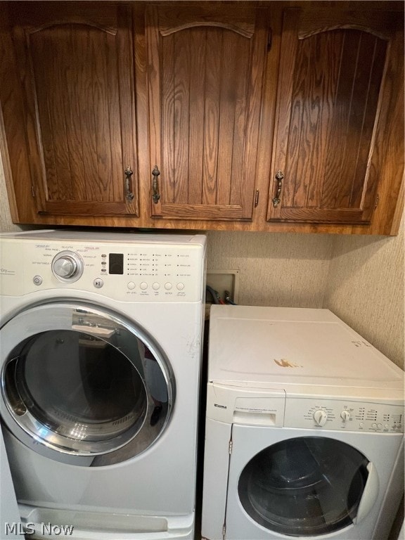 washroom featuring hookup for a washing machine, washer and clothes dryer, and cabinets