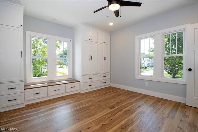 unfurnished bedroom featuring ceiling fan, hardwood / wood-style flooring, and multiple windows