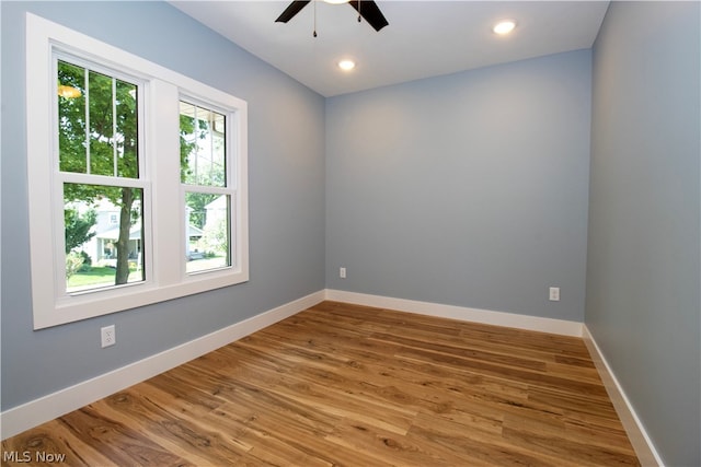 empty room featuring plenty of natural light, ceiling fan, and hardwood / wood-style flooring