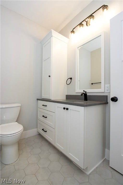 bathroom featuring tile floors, vanity, and toilet