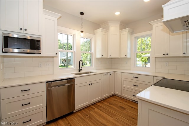 kitchen with stainless steel appliances, hanging light fixtures, tasteful backsplash, wood-type flooring, and sink