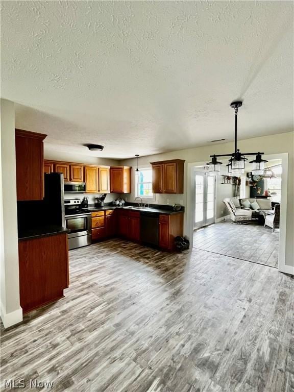 kitchen featuring decorative light fixtures, french doors, sink, stainless steel appliances, and light hardwood / wood-style flooring