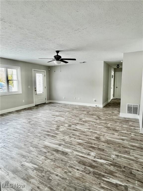 unfurnished living room with a textured ceiling, wood-type flooring, and ceiling fan