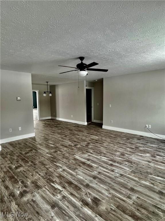 unfurnished living room featuring dark hardwood / wood-style floors, a textured ceiling, and ceiling fan