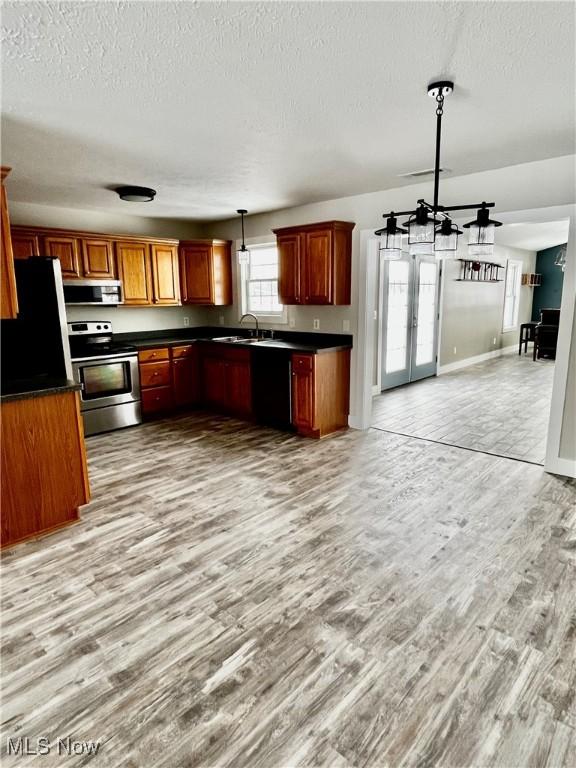 kitchen featuring french doors, sink, light hardwood / wood-style flooring, appliances with stainless steel finishes, and pendant lighting