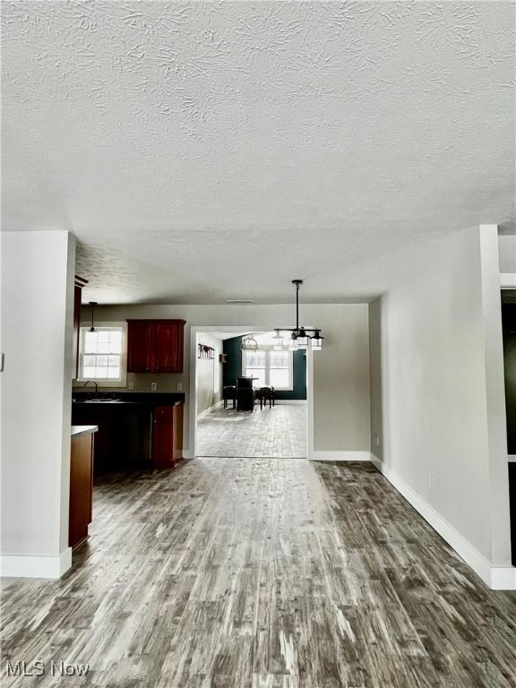 unfurnished living room with dark wood-type flooring, a chandelier, and sink