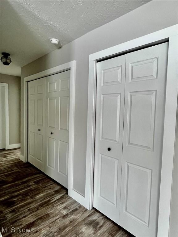 hallway with dark hardwood / wood-style flooring and a textured ceiling