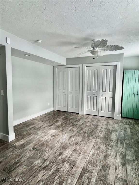 unfurnished bedroom featuring ceiling fan, a textured ceiling, and two closets