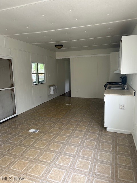 interior space with light countertops, open floor plan, white cabinets, and a sink