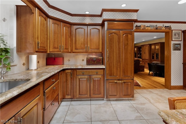 kitchen with light stone counters, sink, light tile patterned floors, and ornamental molding