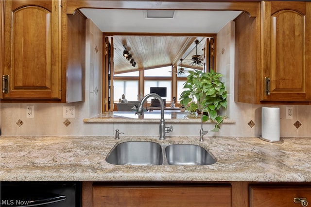 kitchen featuring light stone countertops, dishwasher, and sink