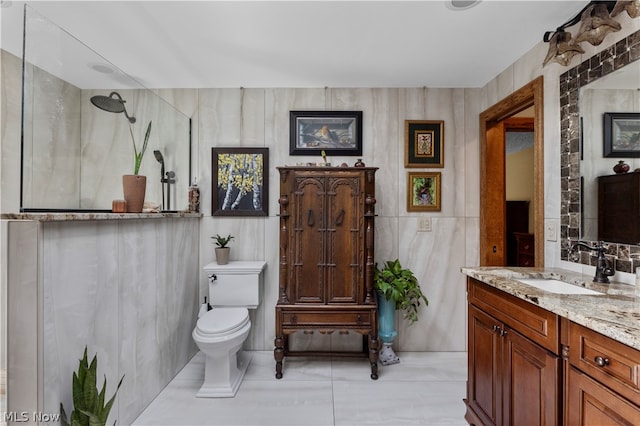 bathroom with walk in shower, vanity, toilet, and tile walls