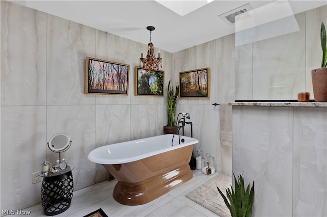 bathroom with tile patterned floors, a tub, tile walls, and a notable chandelier