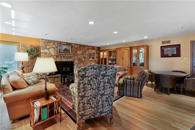 living room with a textured ceiling, light hardwood / wood-style floors, and a fireplace