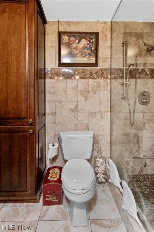 bathroom featuring a tile shower, toilet, and tile walls