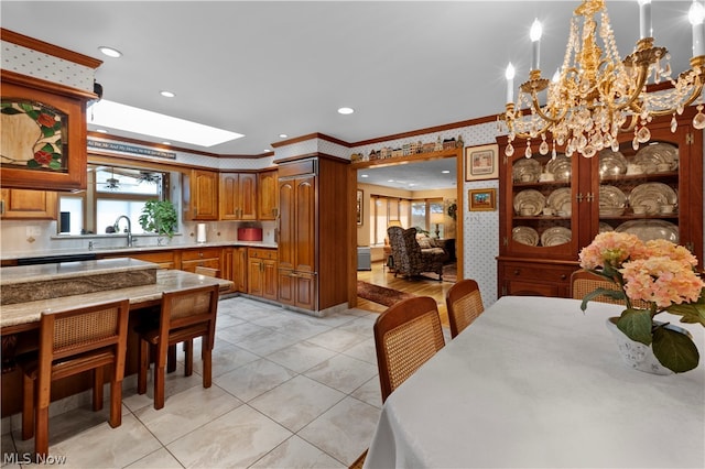 kitchen featuring a skylight, crown molding, sink, and light tile patterned floors