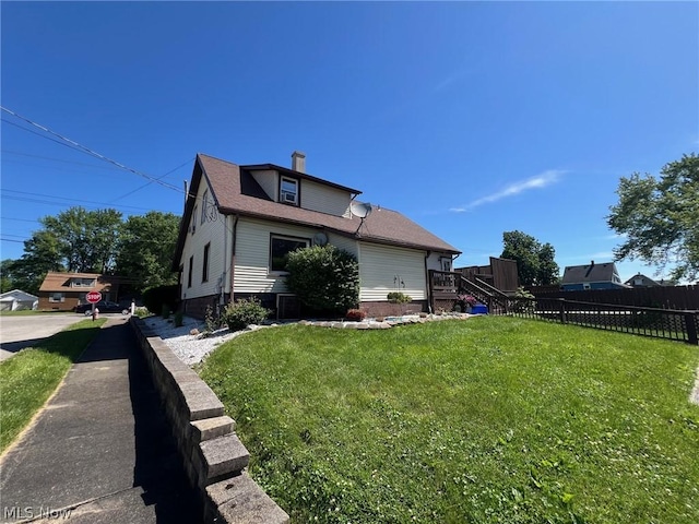 view of property exterior featuring fence, a lawn, roof with shingles, and a chimney