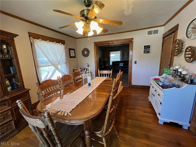 dining space featuring baseboards, visible vents, dark wood finished floors, ceiling fan, and crown molding