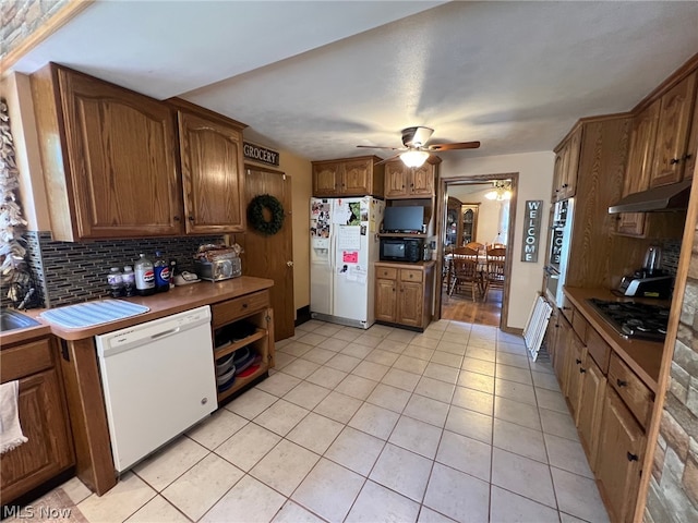 kitchen with black appliances, wall chimney exhaust hood, tasteful backsplash, ceiling fan, and light tile floors