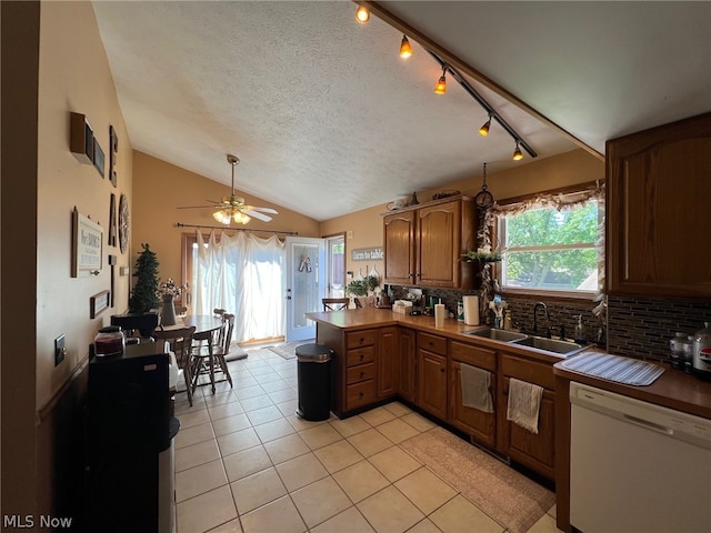 kitchen with vaulted ceiling, light tile flooring, kitchen peninsula, ceiling fan, and white dishwasher