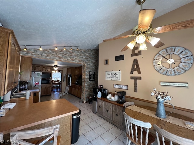 kitchen featuring a textured ceiling, track lighting, ceiling fan, and light tile floors