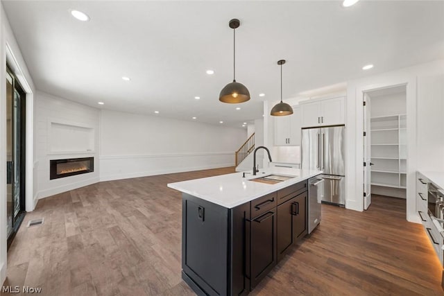 kitchen featuring hanging light fixtures, sink, appliances with stainless steel finishes, dark hardwood / wood-style flooring, and white cabinetry