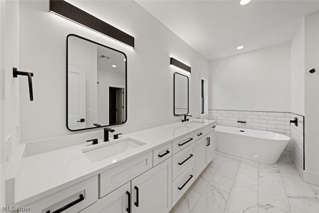 bathroom with vanity, a bath, and tile walls