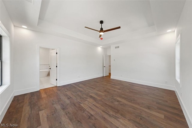 unfurnished room with a tray ceiling, ceiling fan, and dark hardwood / wood-style floors