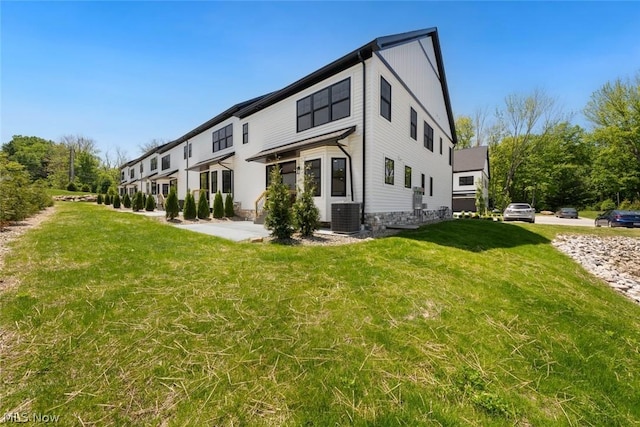 view of side of property with a lawn and central AC