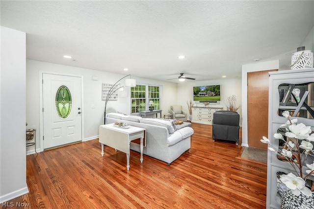 living room featuring hardwood / wood-style floors, ceiling fan, and a textured ceiling