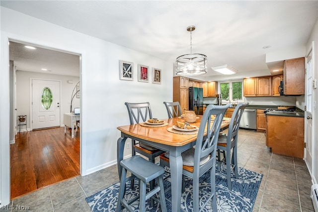 dining room with hardwood / wood-style floors, a baseboard radiator, and an inviting chandelier