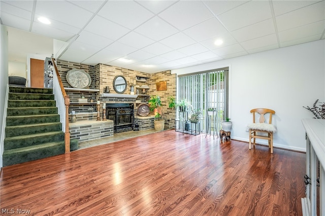 unfurnished living room with a wood stove, hardwood / wood-style floors, and a drop ceiling