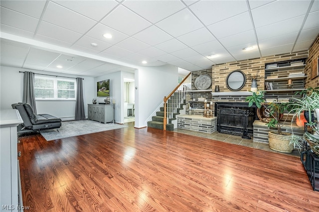 unfurnished living room featuring a fireplace, a paneled ceiling, and hardwood / wood-style flooring