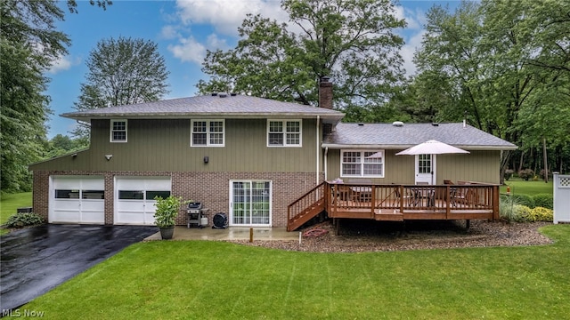 rear view of property with a yard, a garage, and a wooden deck