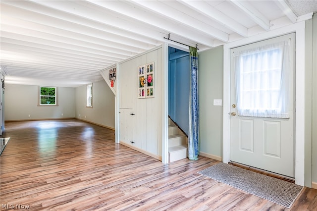 foyer featuring vaulted ceiling with beams and light hardwood / wood-style flooring