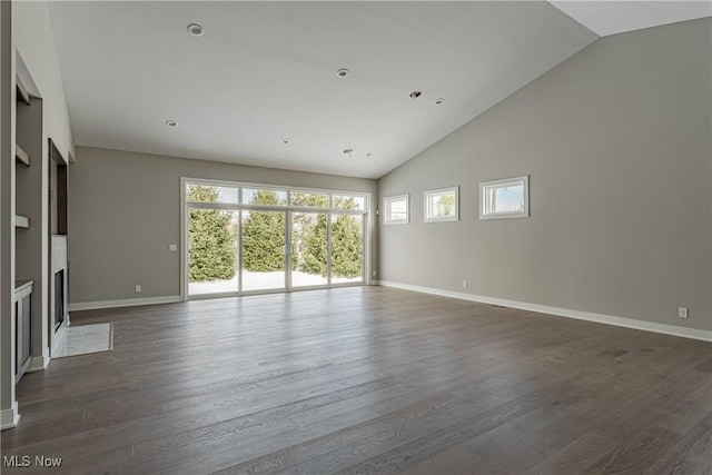 unfurnished living room featuring dark wood-type flooring and high vaulted ceiling