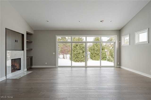 unfurnished living room with wood-type flooring, lofted ceiling, and a premium fireplace