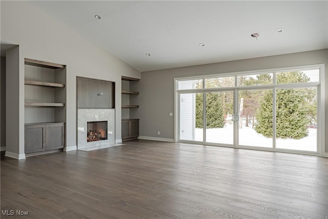 unfurnished living room with built in shelves, a premium fireplace, hardwood / wood-style floors, and high vaulted ceiling