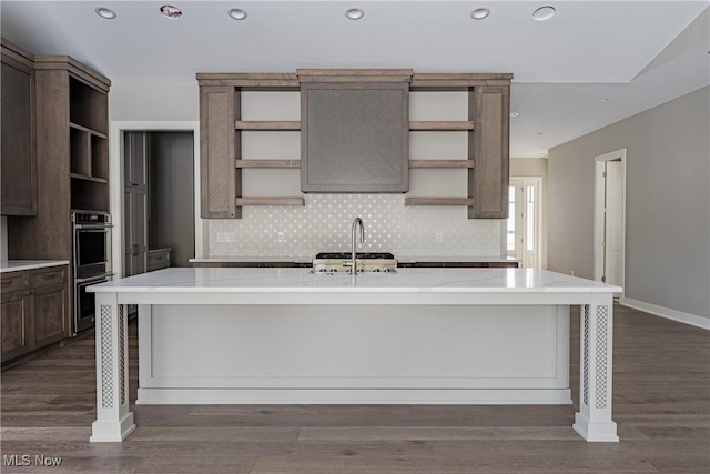 kitchen featuring a kitchen breakfast bar, sink, dark wood-type flooring, and an island with sink