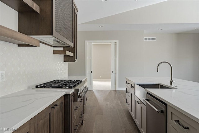 kitchen featuring light stone countertops, wood-type flooring, stainless steel appliances, and sink