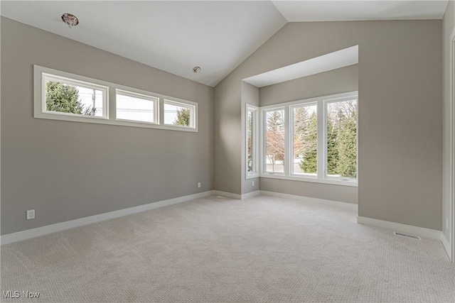 carpeted spare room featuring plenty of natural light and vaulted ceiling