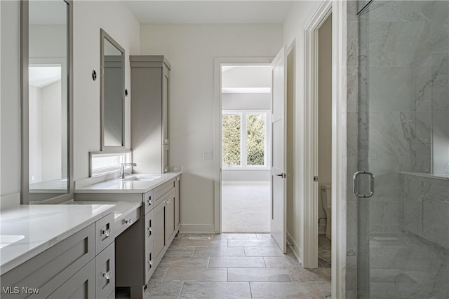 bathroom featuring vanity, toilet, and a shower with shower door