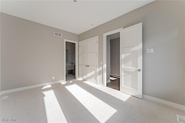 unfurnished bedroom featuring ensuite bathroom and carpet floors