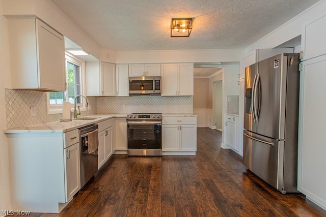 kitchen with backsplash, white cabinets, sink, dark hardwood / wood-style floors, and stainless steel appliances