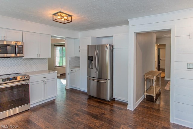 kitchen with dark hardwood / wood-style floors, backsplash, appliances with stainless steel finishes, white cabinets, and ornamental molding