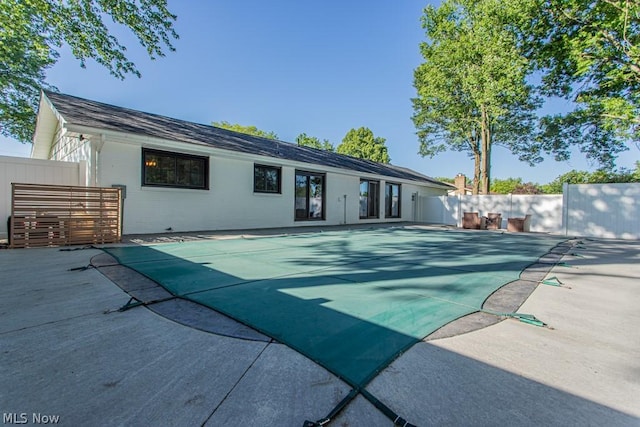 rear view of house with a covered pool and a patio area