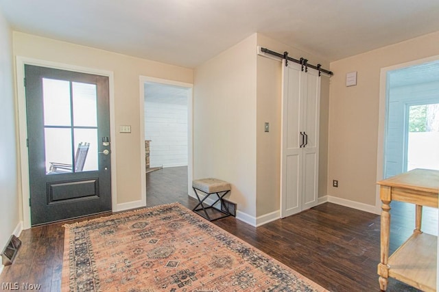 foyer entrance with a barn door and dark hardwood / wood-style flooring