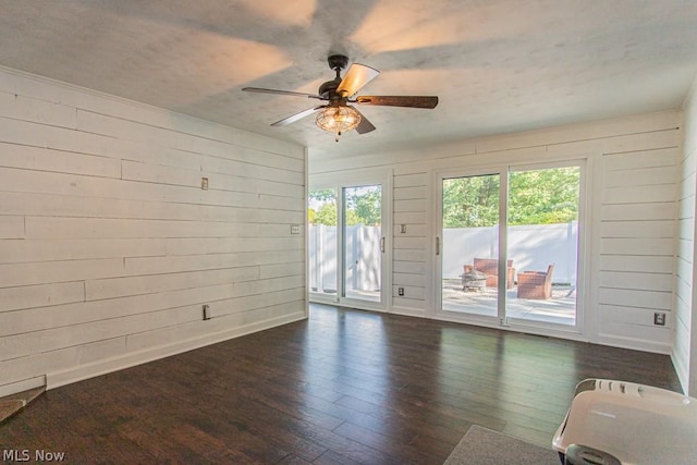 spare room with dark hardwood / wood-style floors, ceiling fan, and wooden walls